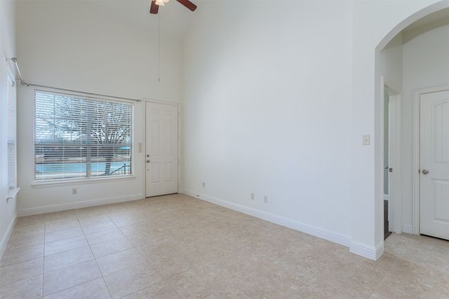 Spare room with high vaulted ceiling, a ceiling fan, arched walkways, light tile patterned floors, and baseboards | Image 6