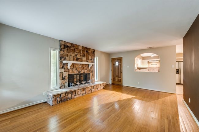 living room with a fireplace, baseboards, visible vents, arched walkways, and hardwood / wood-style floors | Image 8