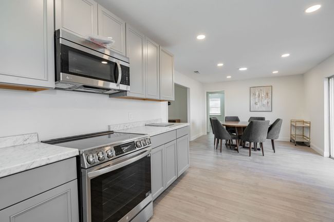 Kitchen with appliances with stainless steel finishes, recessed lighting, light wood finished floors, gray cabinetry, and light stone counters | Image 11
