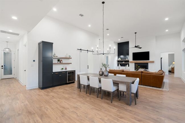 Dining room with wine cooler, a bar, light wood-type flooring, recessed lighting, and a large fireplace | Image 8