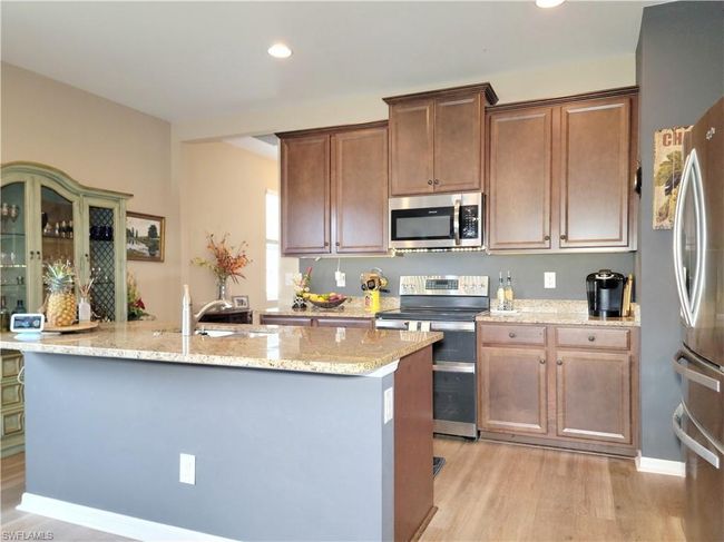 Kitchen featuring recessed lighting, light stone counters, a center island with sink, light wood-style flooring, and appliances with stainless steel finishes | Image 14