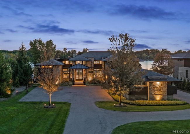 Modern home featuring stone siding, curved driveway, a chimney, and a front lawn | Image 56