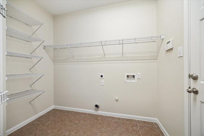 A dedicated laundry room offers convenience with space for a washer and dryer, plus additional shelving options for pantry and laundry essentials. | Image 23