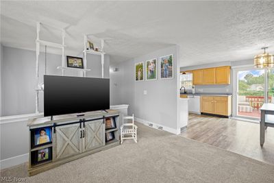 Living room with sink, light wood-type flooring, a notable chandelier, and a textured ceiling | Image 3