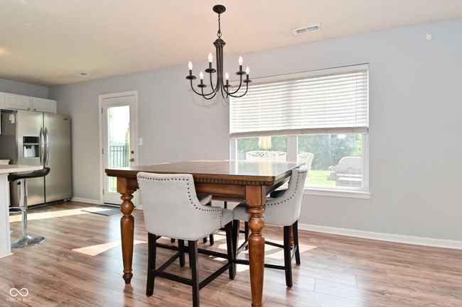 dining space with a chandelier, light wood-type flooring, and baseboards | Image 16