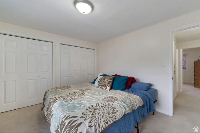Bedroom with baseboards, two closets, and light colored carpet | Image 6