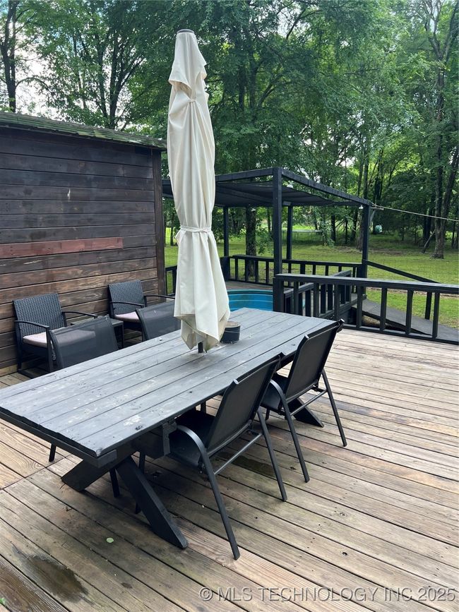 Deck featuring outdoor dining area, view of scattered trees, and fence | Image 30