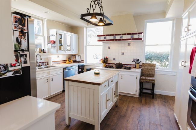 Kitchen with decorative light fixtures, range hood, white cabinetry, and a center island | Image 17