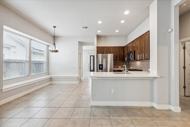 Kitchen featuring appliances with stainless steel finishes, recessed lighting, decorative backsplash, light countertops, and light tile patterned floors | Image 10