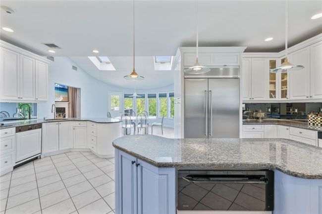 Kitchen featuring built in refrigerator, dishwasher, a skylight, a sink, and white cabinetry | Image 14