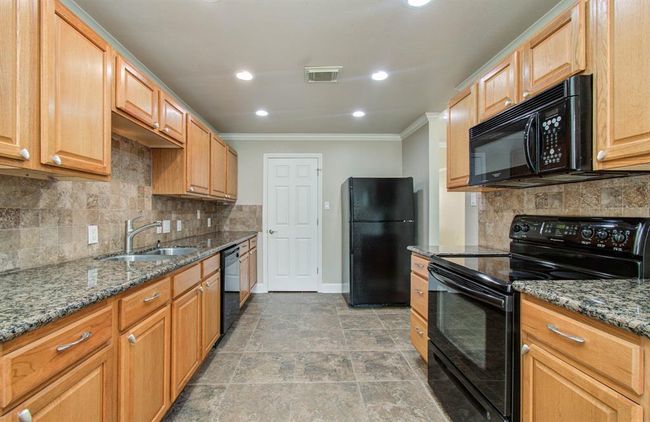 Spacious kitchen with sleek granite countertops, warm wood cabinetry, and modern appliances, perfect for culinary enthusiasts. | Image 8