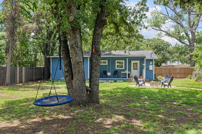 Rear view of house featuring a fire pit, a trampoline, a fenced backyard, and a patio area | Image 23