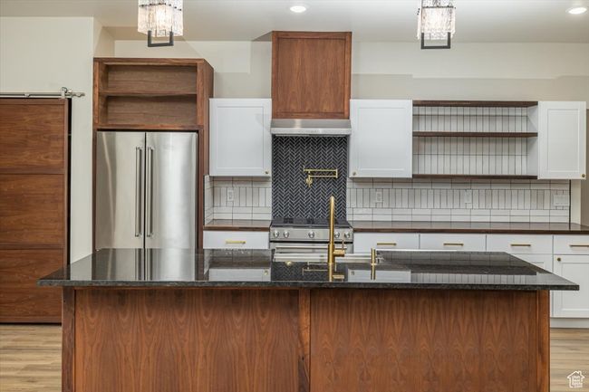 Kitchen featuring white cabinetry, a center island, premium appliances, tasteful backsplash, and light hardwood / wood-style flooring | Image 9