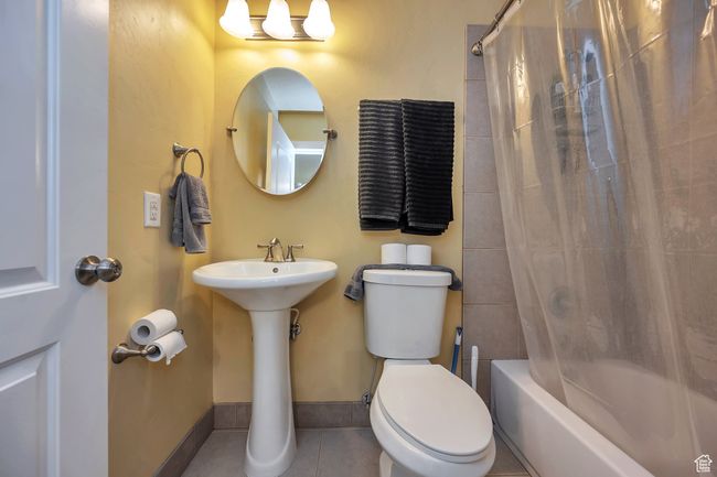 Bathroom featuring baseboards, shower / bath combo with shower curtain, toilet, and tile patterned flooring | Image 19