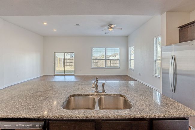Kitchen featuring open floor plan, a sink, ceiling fan, freestanding refrigerator, and dark brown cabinets | Image 7