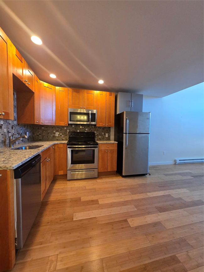 Kitchen featuring dishwashing machine, stove, a sink, fridge, and light stone countertops | Image 14