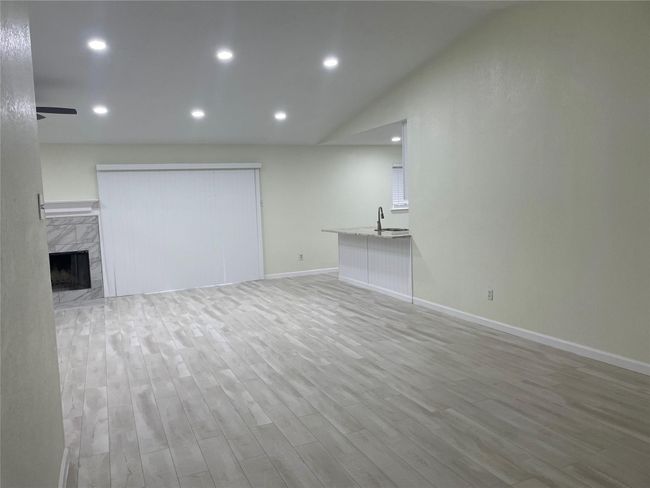 Unfurnished living room featuring wood finished floors, baseboards, a sink, recessed lighting, and a high end fireplace | Image 27
