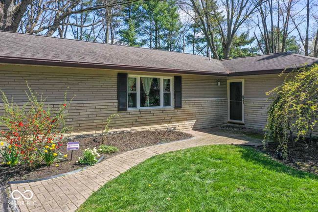 doorway to property with a shingled roof, a lawn, a patio area, and brick siding | Image 4