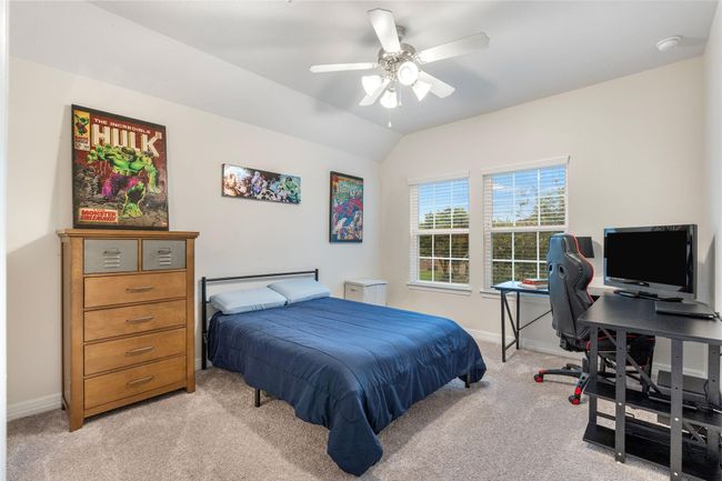 This bedroom features neutral walls, a ceiling fan, and large windows for natural light for a comfortable and functional space. | Image 33