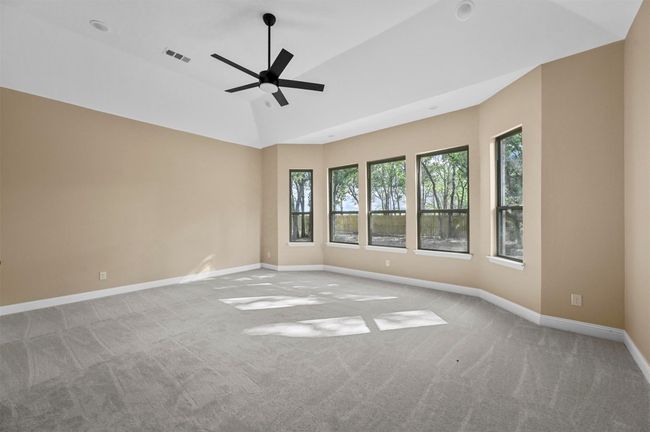 Carpeted spare room featuring vaulted ceiling, a ceiling fan, visible vents, and baseboards | Image 34