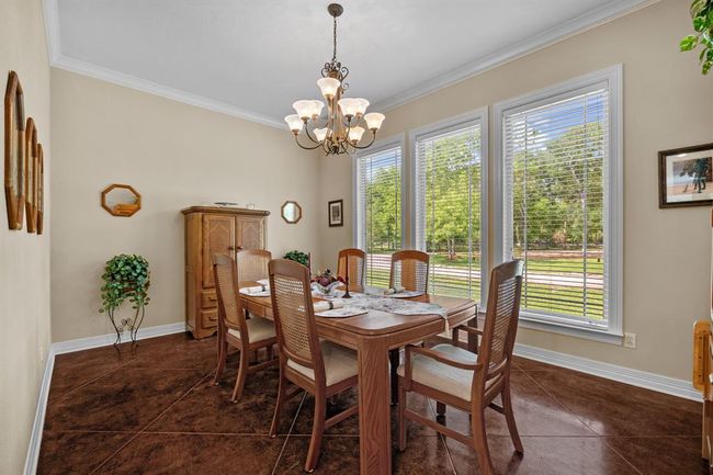 Elegant formal dining space anchored by three wall-to-wall windows that showcase sweeping views of the manicured front lawn. | Image 21