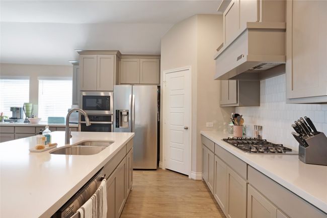 Kitchen featuring stainless steel appliances, light countertops, backsplash, light wood-style floors, and gray cabinets | Image 7