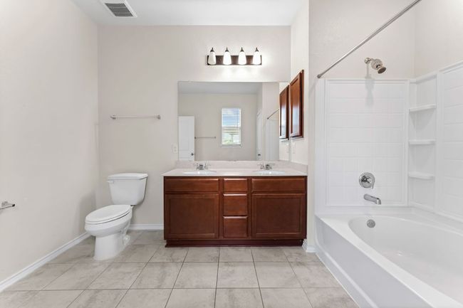 Primary bathroom with tile patterned flooring, double vanity, and washtub / shower combination | Image 18