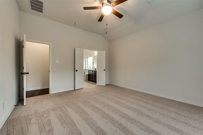 Unfurnished bedroom with light colored carpet, vaulted ceiling, ensuite bathroom, and ceiling fan | Image 12