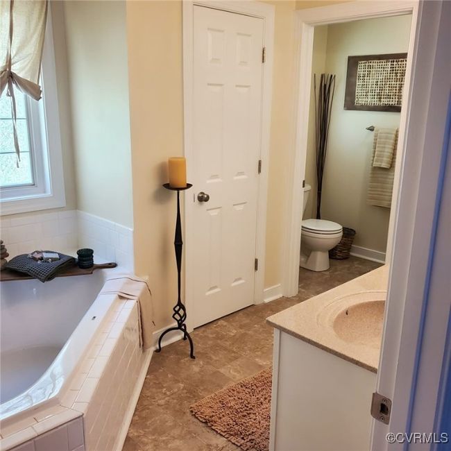 Full bathroom with toilet, a bath, vanity, and baseboards | Image 39