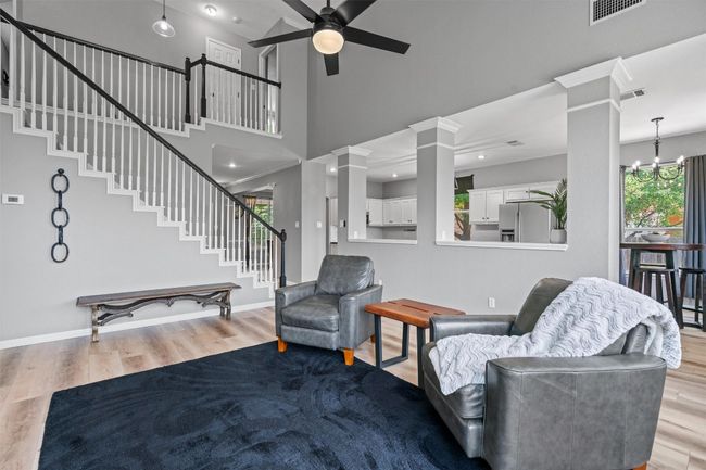 Living room with ornate columns, stairs, a ceiling fan, plenty of natural light, and a towering ceiling | Image 8
