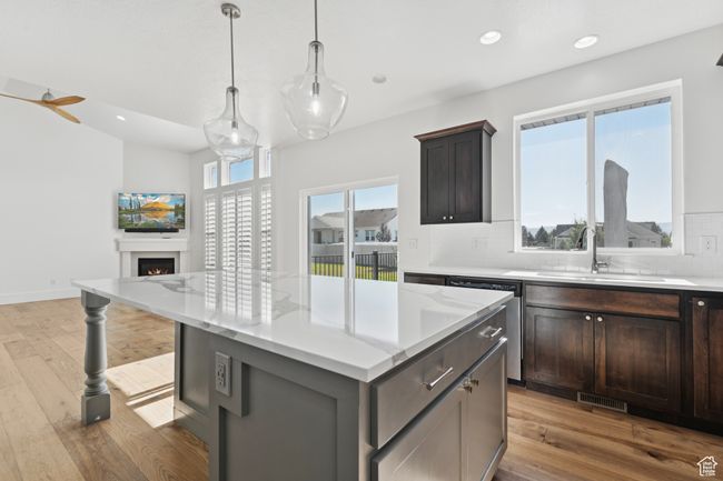 Kitchen featuring stainless steel dishwasher, backsplash, light wood-style floors, a center island, and recessed lighting | Image 10