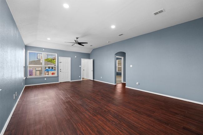 Unfurnished living room with visible vents, baseboards, arched walkways, a ceiling fan, and wood finished floors | Image 16