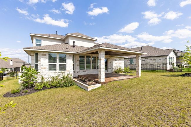 Rear view of property with a patio area, stone siding, and roof with shingles | Image 31