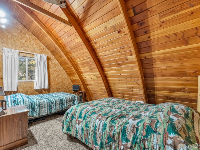 Bedroom with wood ceiling, carpet flooring, and wooden walls | Image 16