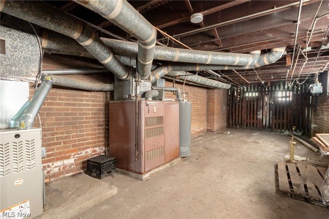 Basement with brick wall, water heater, and heating utilities | Image 27