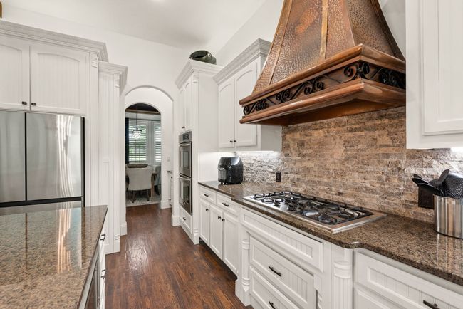 Kitchen featuring stainless steel appliances including double ovens and a 6 burner gas cooktop, a premium range hood, pots and pans drawers, and walk in pantry | Image 12