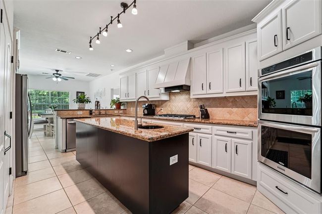 Chef's kitchen includes double ovens, gas range, and an additional prep sink in the island. | Image 10