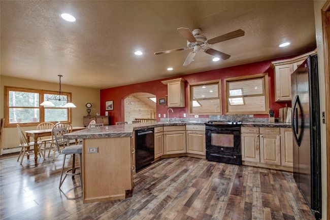 Kitchen with black appliances, a peninsula, light brown cabinets. Great for entertaining. | Image 15