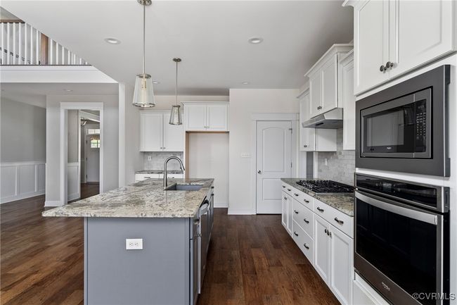 Kitchen with appliances with stainless steel finishes, white cabinetry, tasteful backsplash, dark wood-style floors, and wainscoting | Image 11