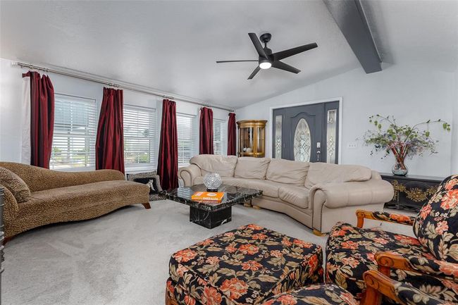 Living room with carpet floors, ceiling fan, and vaulted ceiling with beams | Image 7