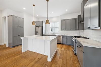 Equipped with modern appliances, porcelain countertops, and custom cabinetry, offering a sleek and functional space for cooking and socializing. | Image 3