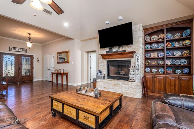 Living area featuring crown molding, ceiling fan, a fireplace, dark wood finished floors, and baseboards | Image 9