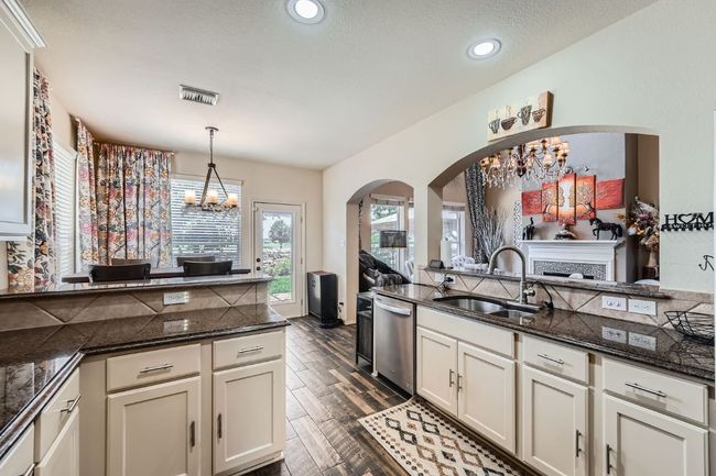 Kitchen with a chandelier, arched walkways, dark wood-type flooring, pendant lighting, and recessed lighting | Image 13