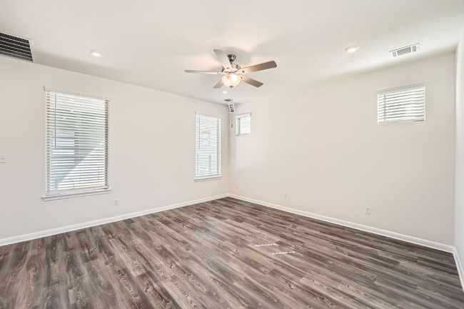 Spare room with a ceiling fan, dark wood-style floors, baseboards, and visible vents | Image 5