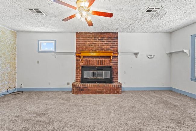 Unfurnished living room with a fireplace, a textured ceiling, ceiling fan, and carpet flooring | Image 11