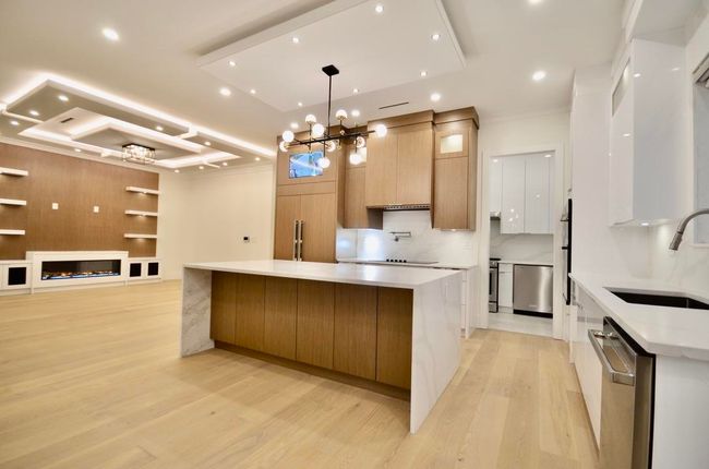 Kitchen with modern cabinets, dishwasher, a chandelier, light wood-type flooring, and a spacious island | Image 4