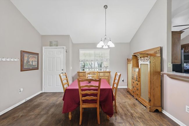 Dining area featuring baseboards, dark wood-type flooring, vaulted ceiling, and a notable chandelier | Image 5