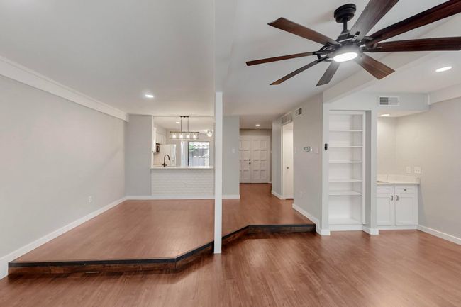 Unfurnished living room with baseboards, visible vents, wood finished floors, and built in features | Image 11