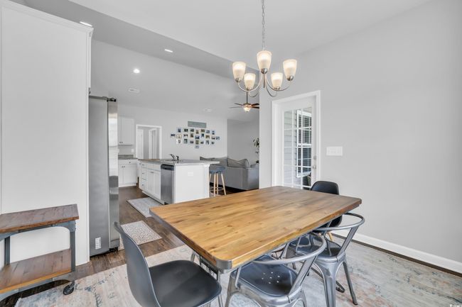 Dining area with a barn door, recessed lighting, wood finished floors, baseboards, and ceiling fan with notable chandelier | Image 25