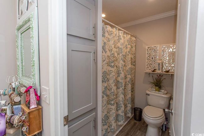 Full bath featuring crown molding, curtained shower, toilet, and wood finished floors | Image 32